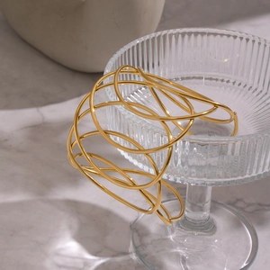 Macro detail of intertwined gold layered bracelet resting on elegant textured glassware