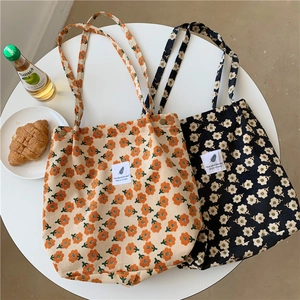 Bolsos tote de pana con flores en beige y negro mostrados con accesorios de estilo
