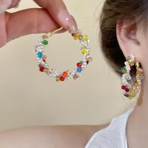 Gros plan de perles en verre coloré et perles tressées sur une boucle d'oreille