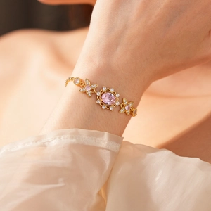Macro detail of a vintage gold bracelet featuring a pink oval gem and white zircons