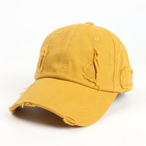 Close-up of vintage distressed details and ripped cotton fabric on yellow baseball cap
