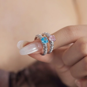Macro shot of square-cut light blue and pink gemstones on silver bands with side stones