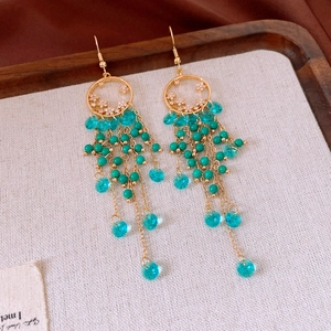 Detail of ethnic tassel earrings with turquoise beads and crystals in a wooden tray