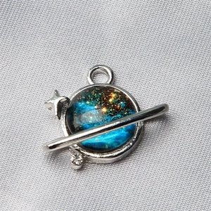 Macro shot of a planet charm with star nebula patterns on silver satin fabric