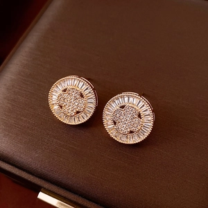 Macro shot of 18k gold plated round earrings with sparkling zircon on a leather box