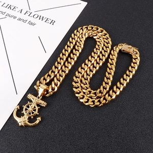 Collier gourmette en acier titane doré avec pendentif croix et ancre sur fond noir