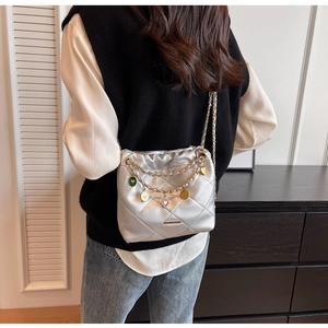 Detail of silver quilted bucket bag with gold chain strap and colorful charms for women