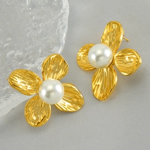 French style gold flower stud earrings with white pearl center on textured fabric