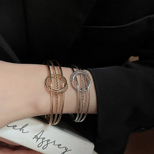 Close-up of layered irregular twisted metal bangles in gold and silver on a model