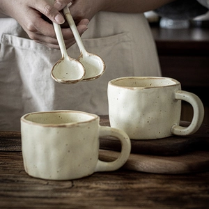 Handmade ceramic mug set with brown speckles and matching spoons in rustic kitchen