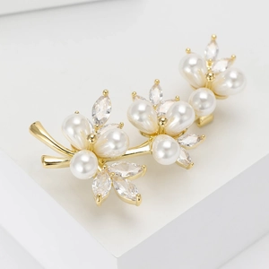 Detail of golden floral brooch with white pearls and marquise cubic zirconia stones