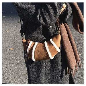 Detail der braunen Wildleder-Hörnchentasche mit weißen Pelzstreifen und Knotenträger