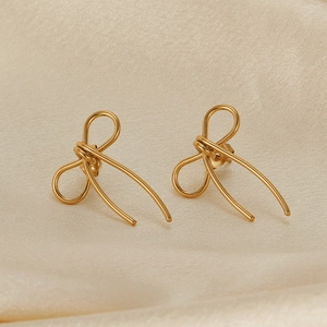 Detailed view of elegant gold bow earrings crafted from stainless steel on fabric