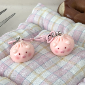 Close-up of cute pink piglet-shaped steamed bun keychains on a checkered mat