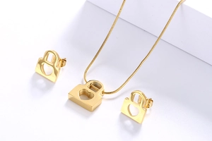 Detailed close-up of gold hollow heart lock necklace and matching stud earrings set