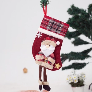 Detail of red Christmas stocking with plaid patterns, plush trim, and Santa doll