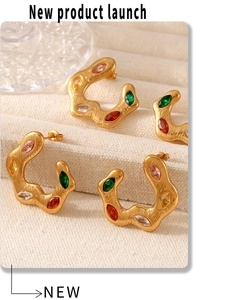 Close-up of gold C-shaped earrings featuring colorful marquise stones and brushed texture