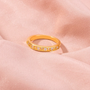 Detail showing gold ring with pavé zircons and milgrain edge on pink silk background