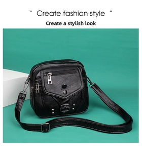 Détail du sac bandoulière noir avec texture grainée, rivets argentés et fermetures éclair