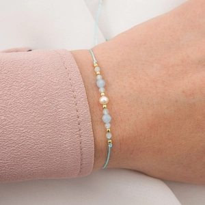Handmade beaded bracelet with natural blue stone and white pearl on light blue cord