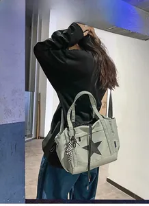 Detail of light green tote bag with star print and checkered charm on a shoulder strap