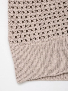Detailed close-up of hollow-out knit pattern and ribbed hem on beige knit vest