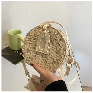 Detail of round straw bag with floral embroidery and adjustable shoulder strap