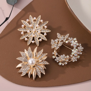 Détail de trois broches florales avec placage doré, cristaux brillants et perles