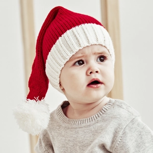 Detail of baby wearing a red knit Christmas hat with white pompom and grey sweater