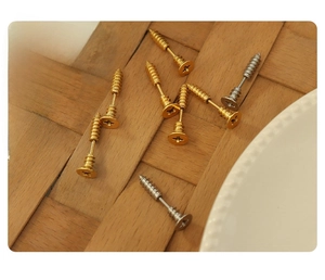 Detail view of gold and silver screw-shaped stud earrings on a vintage background