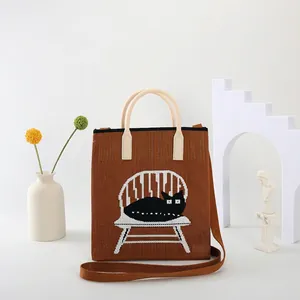 Detailed view of knitted tote bag featuring a black cat pattern with a woven shoulder strap