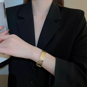 Detail eines breiten goldenen Armreifs mit hochglanzpolierter Oberfläche an einem Modell