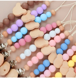 Close-up of wooden bear pacifier clips with colorful silicone beads in various pastel shades
