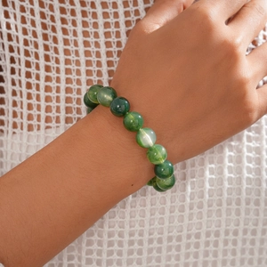 Detail of a green acrylic beaded bracelet featuring smooth semi-transparent marble texture