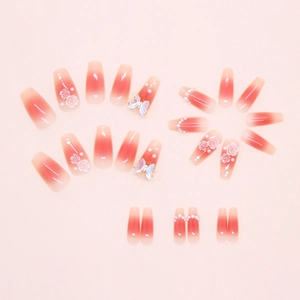 Détail de faux ongles dégradé rose avec roses 3D, perles et papillons irisés élégants