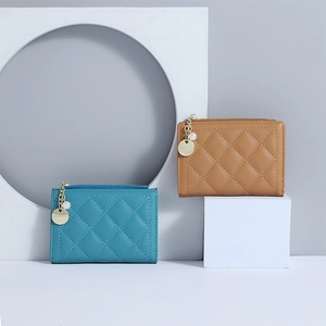 Detail view of teal and camel quilted wallets with elegant pearl zipper pendants