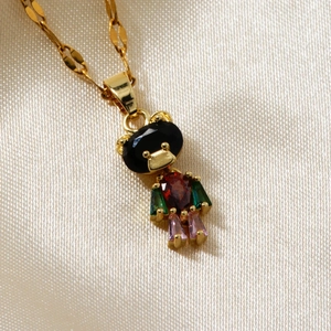 Elegant gold bear pendant necklace with colorful gemstones on white silk background