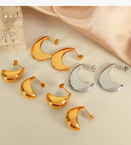 Close-up of polished gold and silver metal teardrop earrings on silk background
