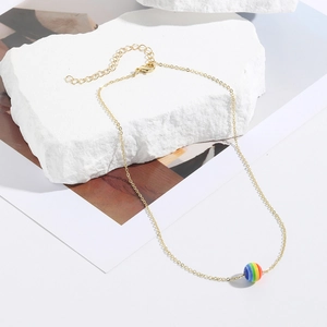 Detail of golden necklace featuring a vibrant rainbow-striped bead and secure lobster clasp