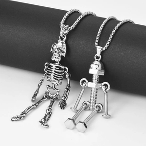 Detail view of vintage silver skeleton and robot pendants hanging on a black stand
