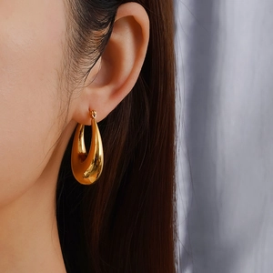 Polished 18K gold-plated stainless steel hollow hoop earrings worn by a model