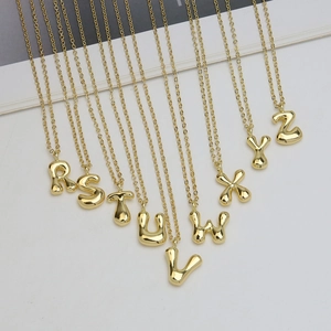 Polished 18k gold plated bubble letter pendants R-Z with fine necklaces on grey background