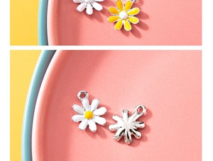 Close-up of alloy daisy pendants with yellow enamel center on a decorative pink plate