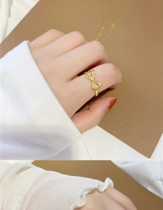 Close-up of a 18K gold plated bow ring worn on index finger with a minimalist design