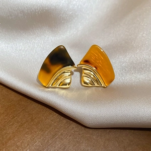 Detailed macro view of 18k gold-plated fan-shaped resin earrings with amber tortoise texture