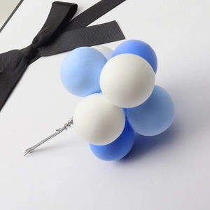 Detail of blue and white clay balloon cake topper with a decorative black ribbon bow