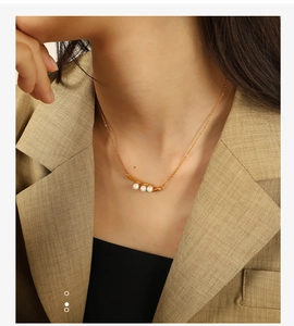 Détail d'un élégant collier en or avec trois perles horizontales sur une chaîne fine