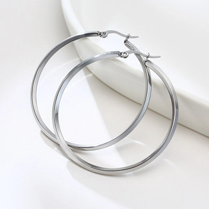 Macro shot of high-polished stainless steel large hoop earrings on white ceramic base