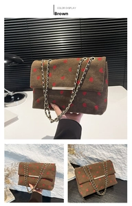 Detail of brown corduroy shoulder bag featuring strawberry patterns and golden chain strap