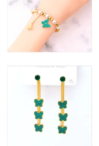 Detail of gold butterfly drop earrings with green emeralds and a pearl bracelet set